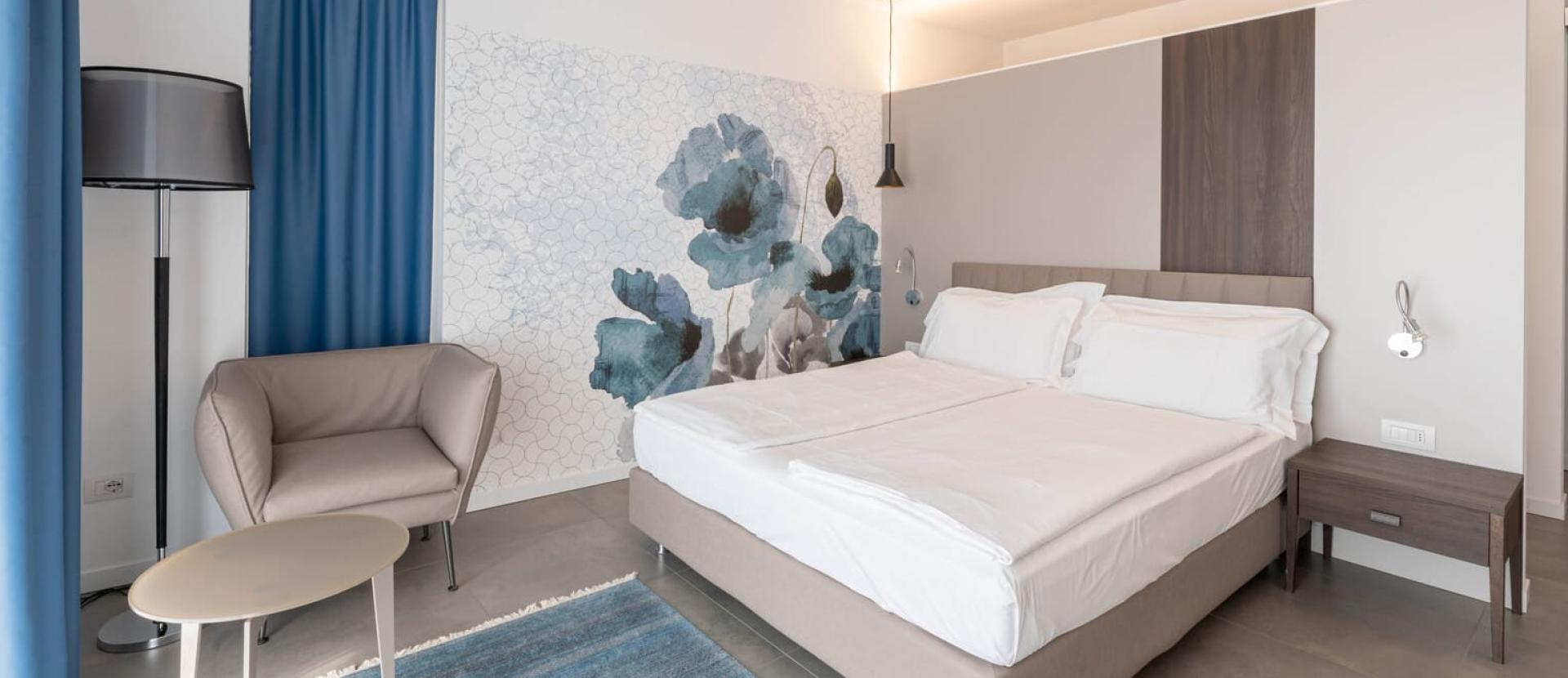 Camera moderna con letto matrimoniale, colori rilassanti e decorazioni floreali blu.