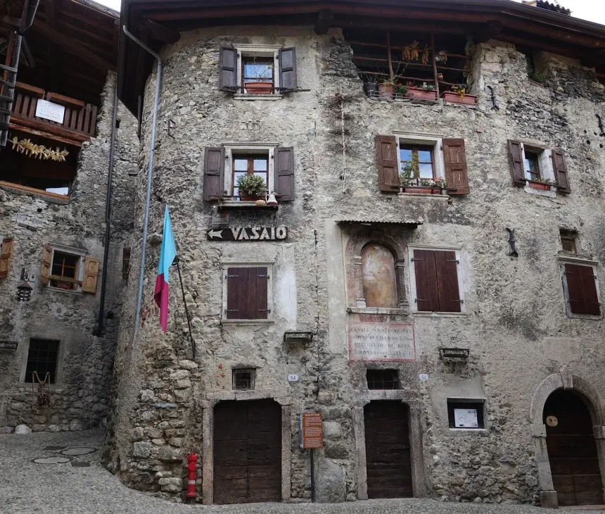 Antico borgo in pietra, finestre fiorite, insegna 'Vasaio', atmosfera rustica e affascinante.