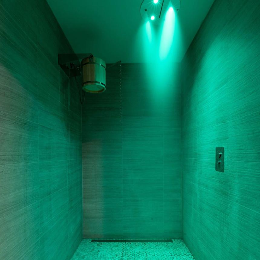 Doccia illuminata di verde, atmosfera rilassante e moderna con pavimento a ciottoli.