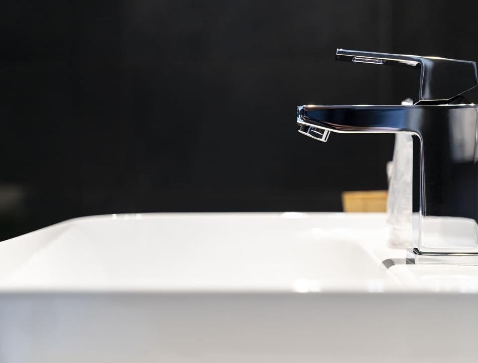 Rubinetto moderno e lucido su lavabo bianco, atmosfera elegante e minimalista.