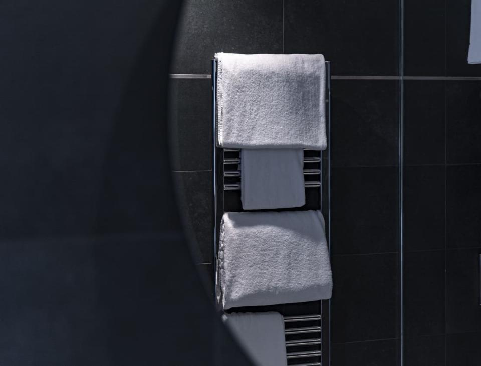 Asciugamani bianchi su portasalviette cromato, in un bagno moderno e rilassante.
