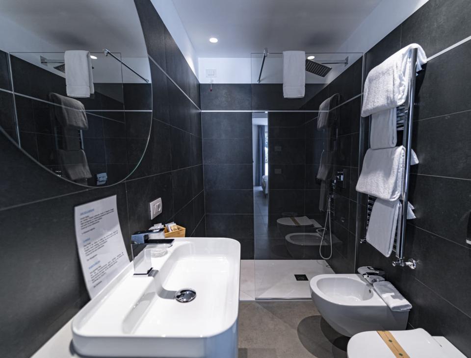 Bagno elegante e moderno, piastrelle scure, doccia spaziosa, atmosfera rilassante e pulita.