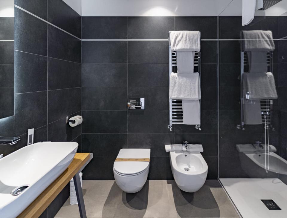 Bagno moderno ed elegante, piastrelle scure, sanitari bianchi, atmosfera ordinata e rilassante.