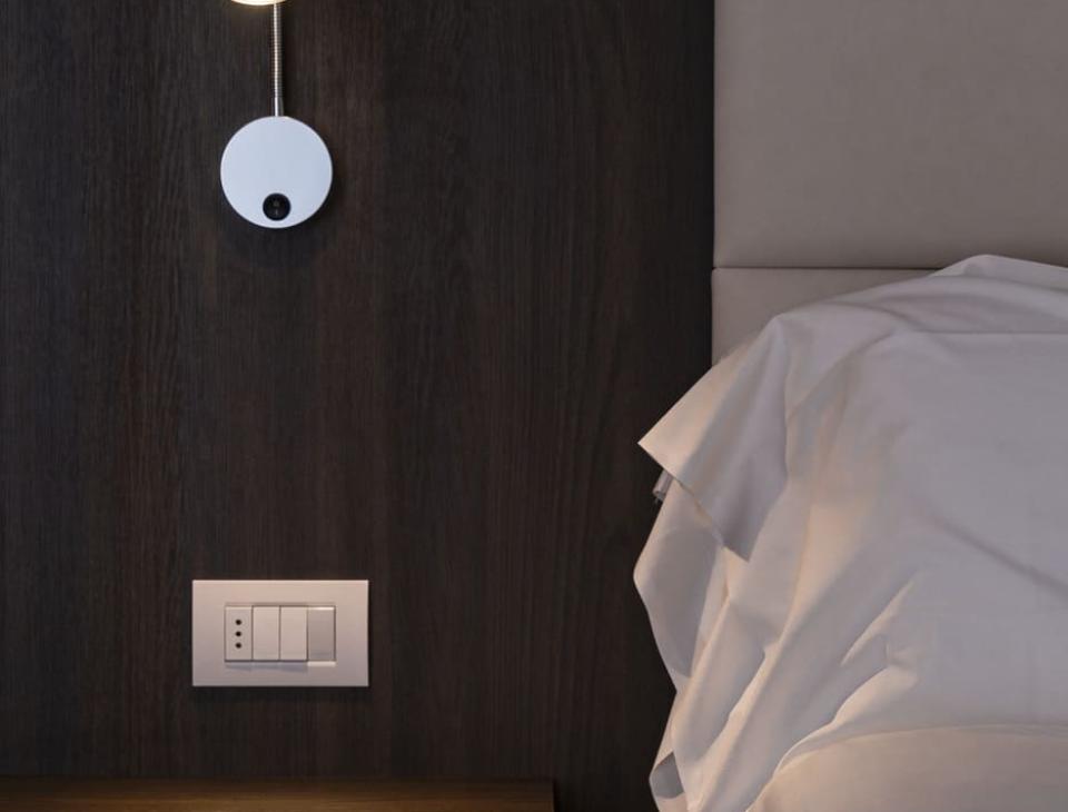 Camera elegante con letto, lampada da lettura e comodino in legno scuro.
