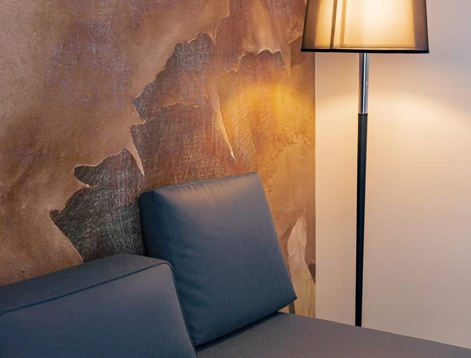 Divano blu e lampada creano un'atmosfera calda e accogliente con parete artistica.
