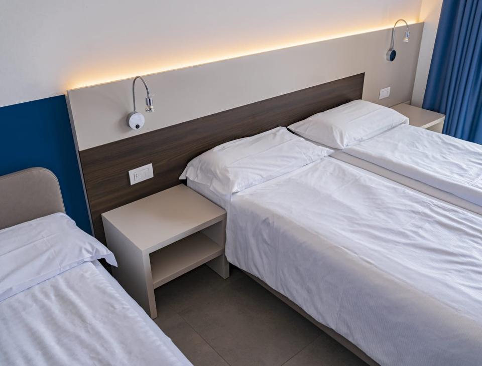 Camera luminosa e ordinata con letti bianchi, atmosfera di tranquillità e comfort.